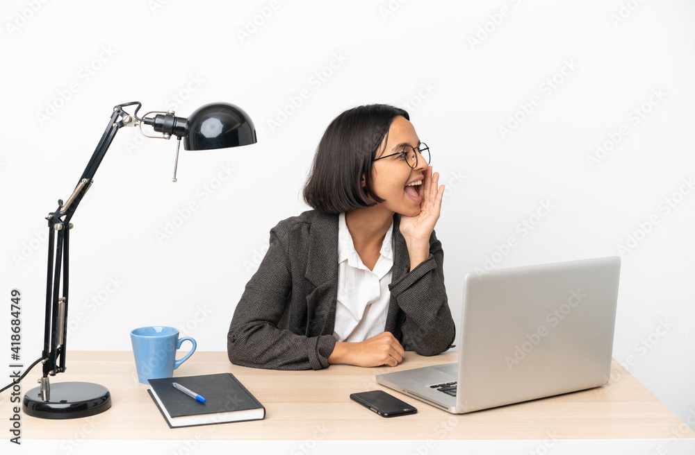 Young business mixed race woman working at office shouting with mouth wide open to the side Young business mixed race woman working at office shouting with mouth wide open to the side