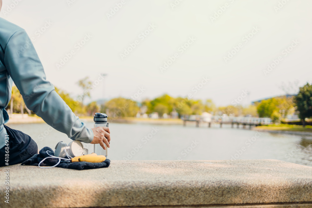 sport man sitting after running and holding water bottle drink. Sport thirsty and resting after exercise.