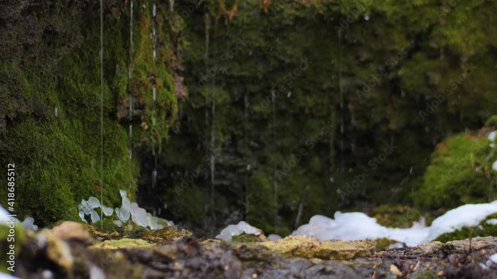 A small river flows into the forest, snowflakes fall into the water A small river flows into the forest, snowflakes fall into the water