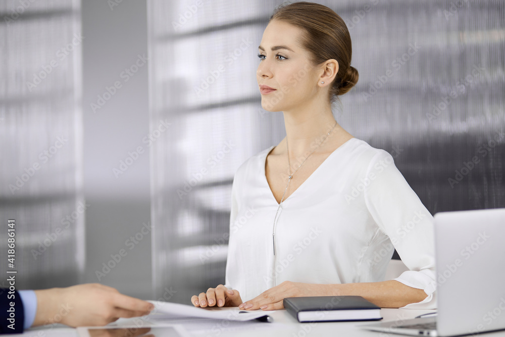 Business people discussing something while sitting in office. Focus at businesswoman while talking to her male colleague. Teamwork and meeting concept Business people discussing something while sitting in office. Focus at businesswoman while talking to her male colleague. Teamwork and meeting concept