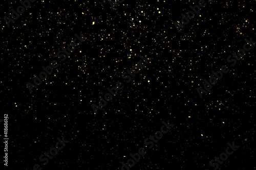 Shiny golden particles on black background