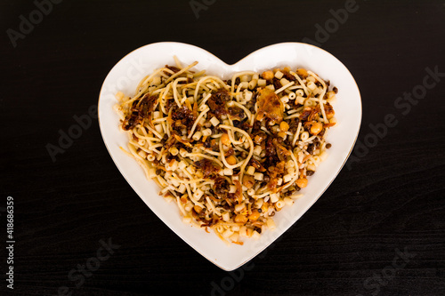 Famous traditional Arabic, Egyptian dish - Koshari. National Kushari in a white plate on dark wooden background. Flat lay, top view. photo