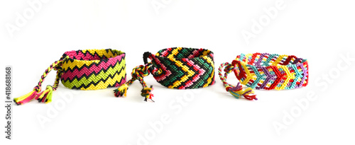 Woven DIY friendship bracelets with bright colorful pattern handmade of thread on white background