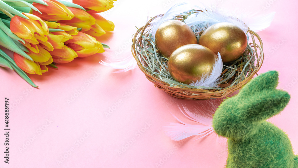 Easter Golden colour eggs in basket with spring tulips, white feathers on pastel pink background in Happy Easter decoration. Festive decoration.