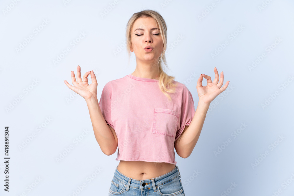 Blonde woman over isolated blue background in zen pose
