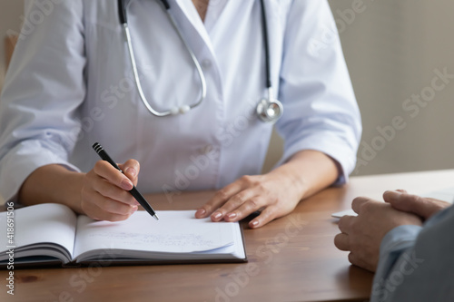 Crop close up of female nurse write prescription in medical journal consult elderly male patient in clinic. Woman doctor or GP handwrite note complains prescribe medicines to mature man in hospital.