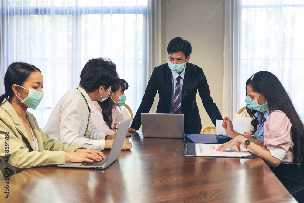 Young business people wear face mask while talking and discussing with coworker team while group meeting and handshake agreement in conference room or office Young business people wear face mask while talking and discussing with coworker team while group meeting and handshake agreement in conference room or office