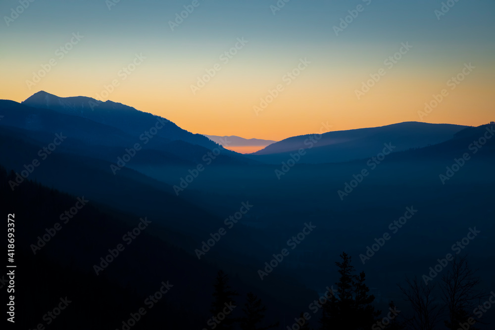 Orange sky over Podhale region, Poland. Shadow areas emphasizing the silhouette of Tatra Mountains. Selective focus on the hills, blurred background.
