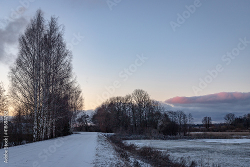 Beautiful orange blue sunset over a snowy road. Winter landscape.