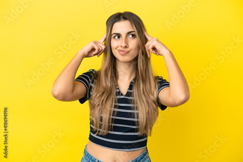 Young caucasian woman isolated on yellow background having doubts and thinking