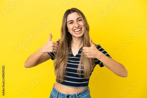 Young caucasian woman isolated on yellow background with thumbs up gesture and smiling