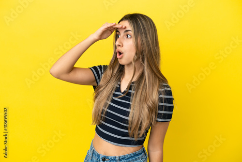 Young caucasian woman isolated on yellow background with surprise expression while looking side