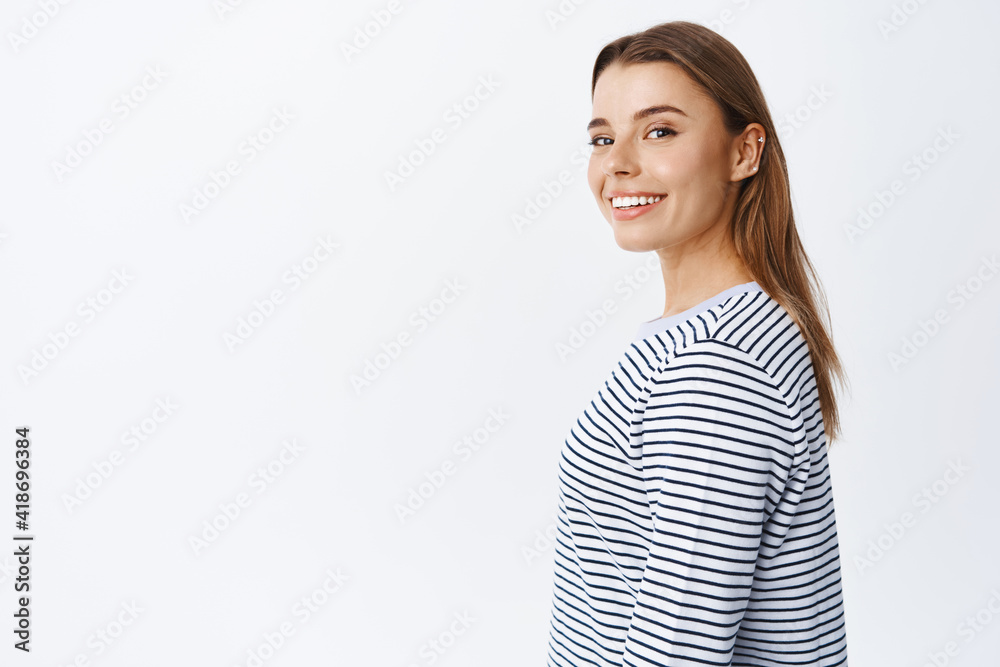 Portrait of good-looking blond girl turn head at camera with cheerful smile, advertising beauty products, standing in casual clothes against white background Portrait of good-looking blond girl turn head at camera with cheerful smile, advertising beauty products, standing in casual clothes against white background