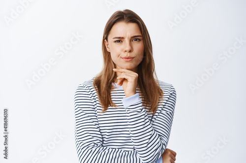 Photo Image of suspicious blond girl squinting and frowning at camera, having doubts o
