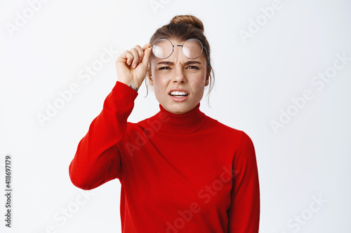 Fotografía Image of confused blond girl take-off glasses and squinting, trying to see somet