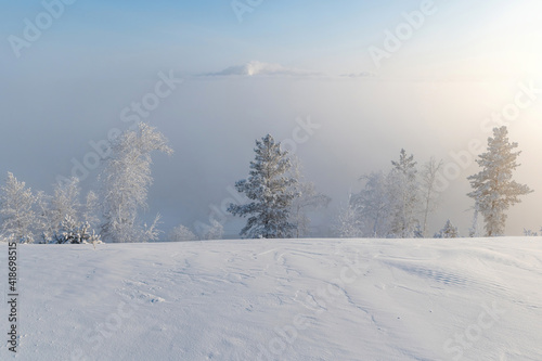 Winter landscape with a view of the city from the hill. The city is hidden under dense fog
