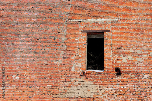 A hole where a door should have been in the old brick wall of a crumbling industrial building. © Maya