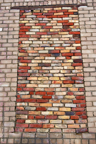 A bricked-up window opening in the brick wall of an old industrial building.