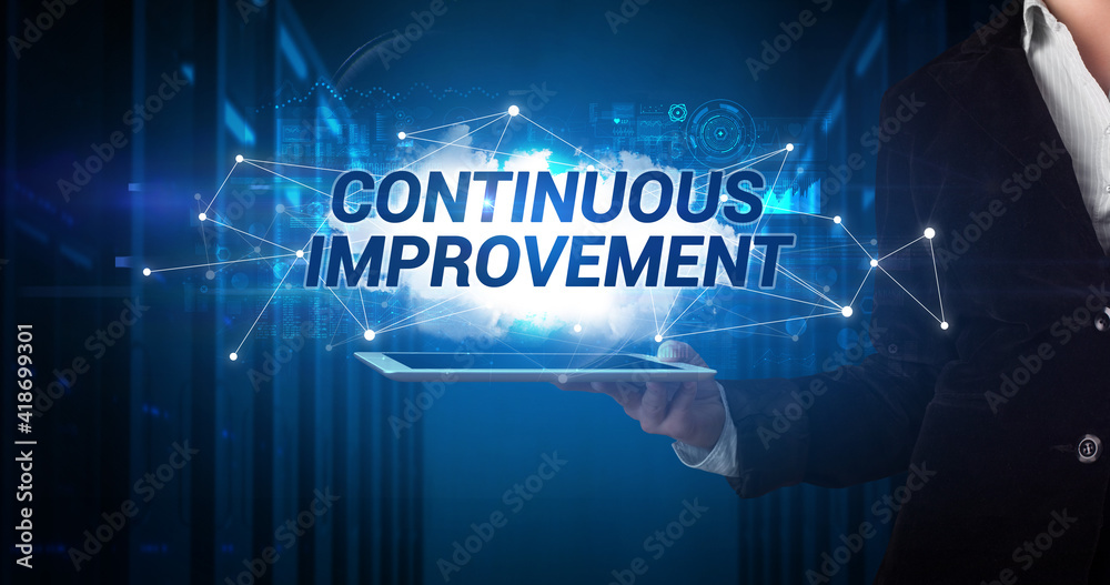 Young business person working on tablet and shows the inscription: CONTINUOUS IMPROVEMENT Young business person working on tablet and shows the inscription: CONTINUOUS IMPROVEMENT