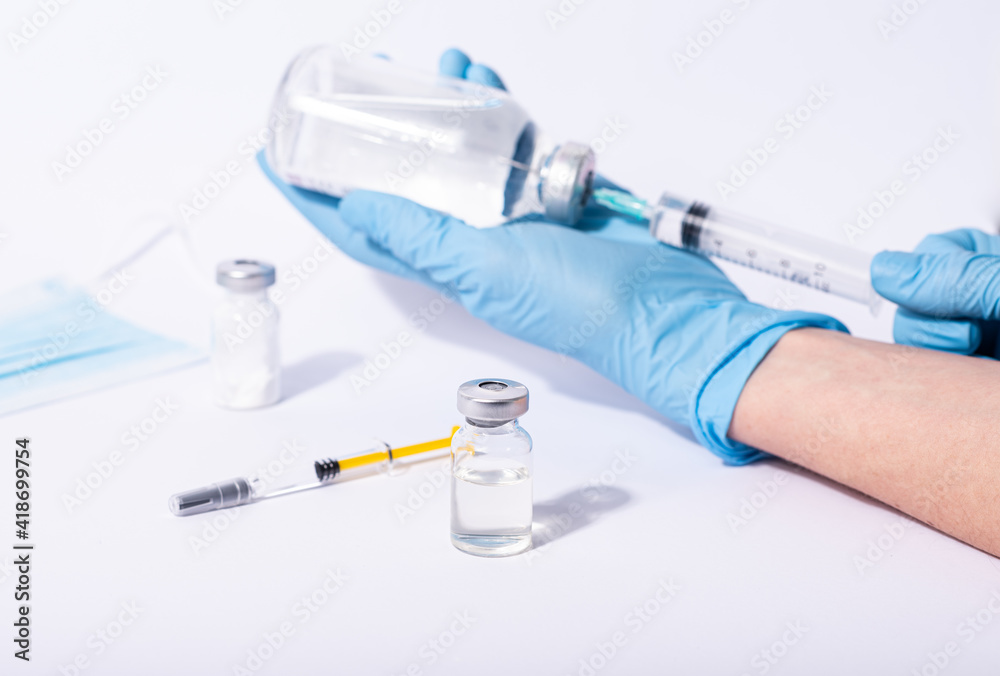 Doctor, researcher holds hands syringe in blue glove holding flu, measles, rubella or hpv vaccine and syringe with needle vaccination for human. Doctor, researcher holds hands syringe in blue glove holding flu, measles, rubella or hpv vaccine and syringe with needle vaccination for human.