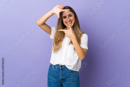 Young woman over isolated purple background focusing face. Framing symbol