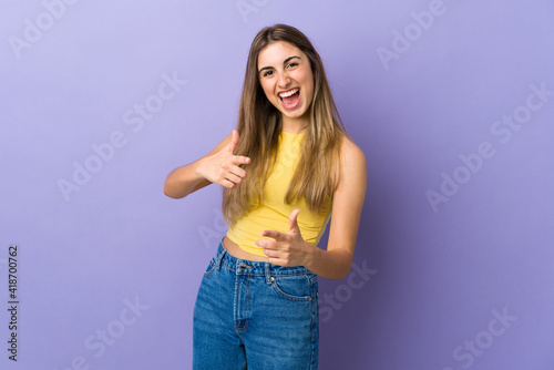 Young woman over isolated purple background pointing to the front and smiling