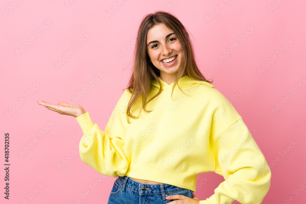 Young woman over isolated pink background presenting an idea while looking smiling towards Young woman over isolated pink background presenting an idea while looking smiling towards