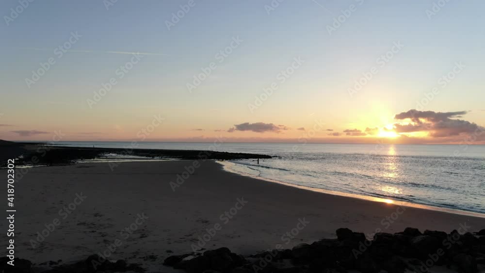 4k dynamic aerial video of sunset on a sand beach with shallow ponds of water, poles, rocks and small pier 4k dynamic aerial video of sunset on a sand beach with shallow ponds of water, poles, rocks and small pier