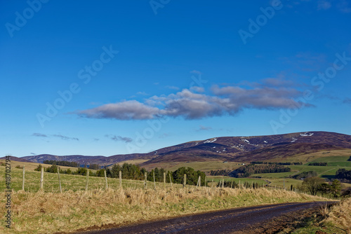 A small Minor Scottish road cuts through the Fields and Countryside of Glen Lethnot in the Angus Glens on a bright Winters morning in February.
