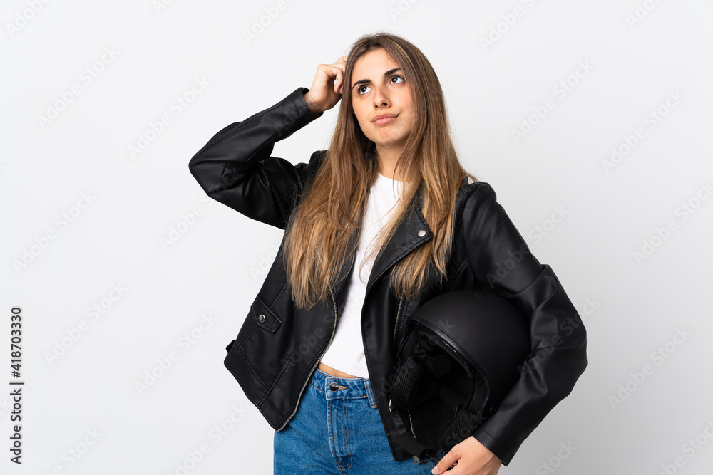 Young Woman holding a motorcycle helmet over isolated white background having doubts and with confuse face expression Young Woman holding a motorcycle helmet over isolated white background having doubts and with confuse face expression