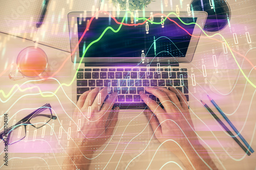 Double exposure of man's hands typing over laptop keyboard and forex chart hologram drawing. Top view. Financial markets concept.