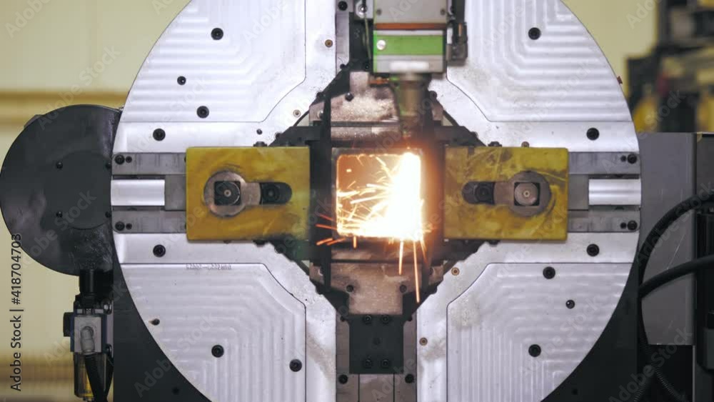 Laser cutting machine for metal pipes. close-up. modern machine with CNC fiber laser is cutting square metal pipe. bright burning sparks fly from laser beam during cutting process