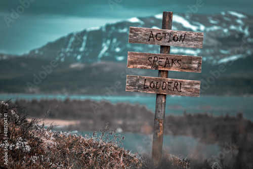 action speaks louder text quote engraved on wooden signpost outdoors in landscape looking polluted and apocalyptic. photo