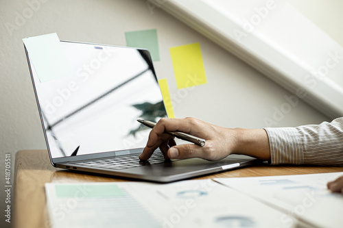 A close-up photo of a businessman typing on a laptop keyboard to examine the company's financial documents prepared by the Finance Department for a meeting with a business partner. Financial concept.
