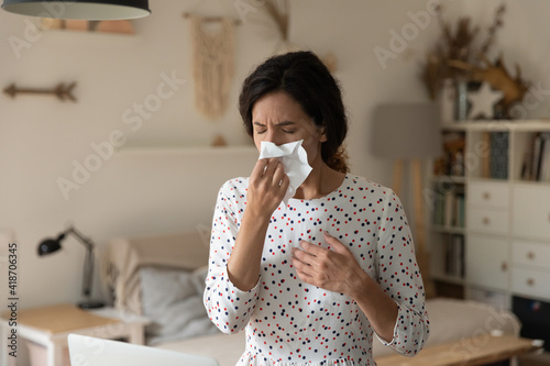Stay at home. Unhealthy ill young female sneeze wipe blow nose with paper tissue suffer of flu rhinitis cold respiratory infection. Sick woman feeling bad having hay fever seasonal allergy aggravation
