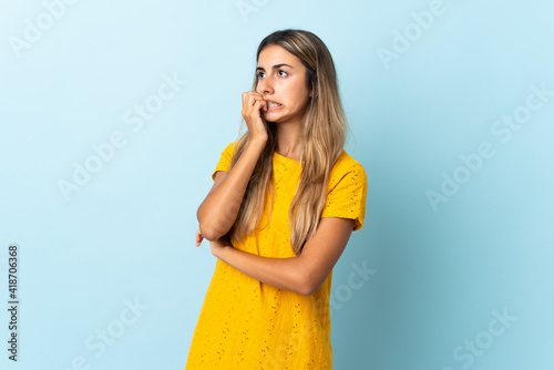 Young hispanic woman over isolated blue background is a little bit nervous