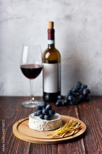Cheese plate served with red wine and grape. Assorted cheeses Camembert and smoke cheese.