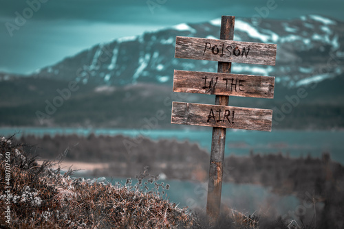 poison in the air text quote engraved on wooden signpost outdoors in landscape looking polluted and apocalyptic. photo