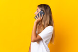 Young hispanic woman over isolated yellow background keeping a conversation with the mobile phone with someone
