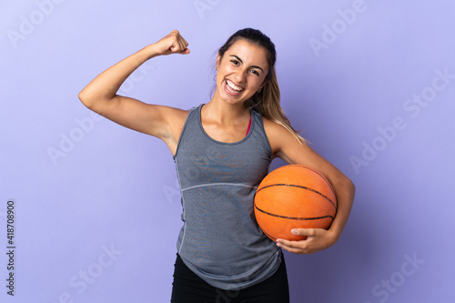Young hispanic woman over isolated purple background playing basketball and proud of himself