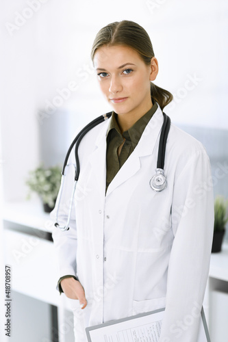 Woman-doctor standing and looking at camera. Perfect medical service in clinic. Medicine and healthcare © Iryna