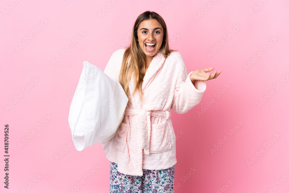 Young hispanic woman over isolated pink background in pajamas and with shocked facial expression Young hispanic woman over isolated pink background in pajamas and with shocked facial expression
