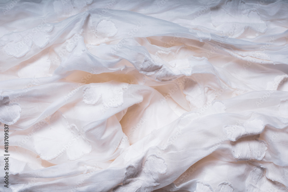 Fototapeta Biała gnieciona tkanina bawełniana. Biała tekstura z kwiatami. Bardzo szczegółowe zbliżenie zmiętej tkaniny.