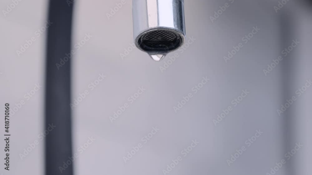 Close up of dripping tap on kitchen. Macro with selective focus on the water drops from a faucet. 4K resolution. Close up of dripping tap on kitchen. Macro with selective focus on the water drops from a faucet. 4K resolution.