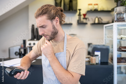 Worried man looking pensively at portable terminal in hand