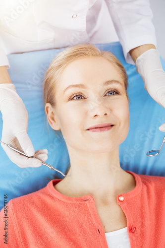 Happy smiling woman is being examined by dentist at dental clinic. Healthy teeth and medicine  stomatology concept