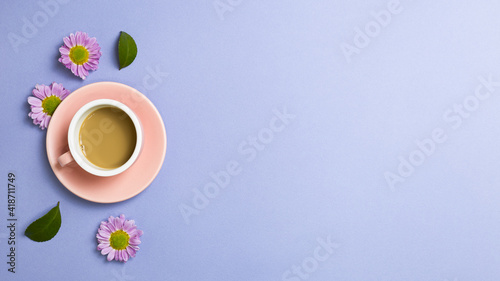 Cup of coffee with flowers on purple background. flat lay, top view, copy space
