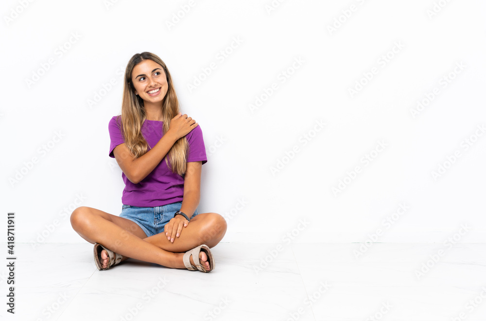Young hispanic woman sitting on the floor looking up while smiling Young hispanic woman sitting on the floor looking up while smiling