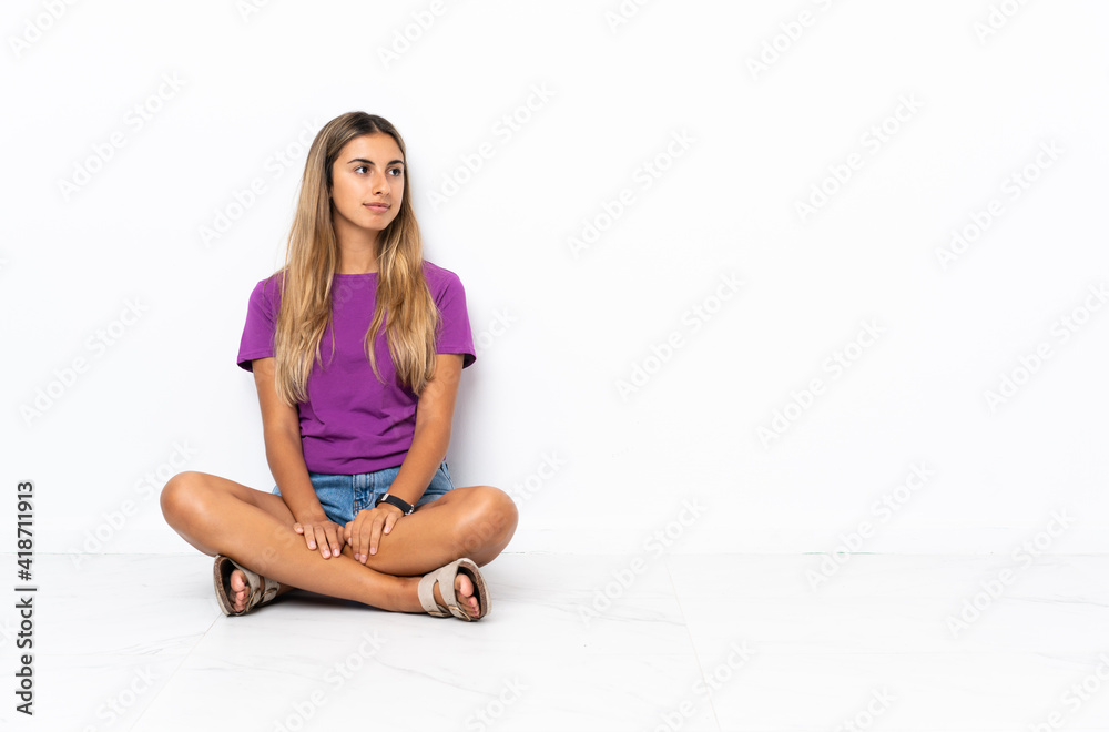 Young hispanic woman sitting on the floor looking to the side Young hispanic woman sitting on the floor looking to the side