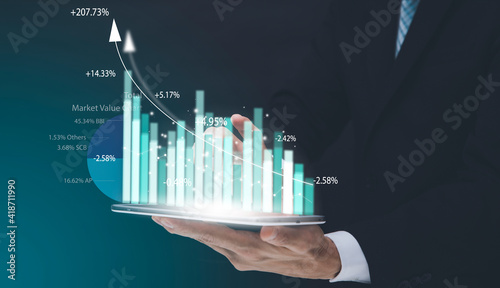 Businessman holding tablet bar graph of analytics and financial, Changes in new planning, Business growth, ideas and perspectives, Stock investment, and dividends yield from business in the new year